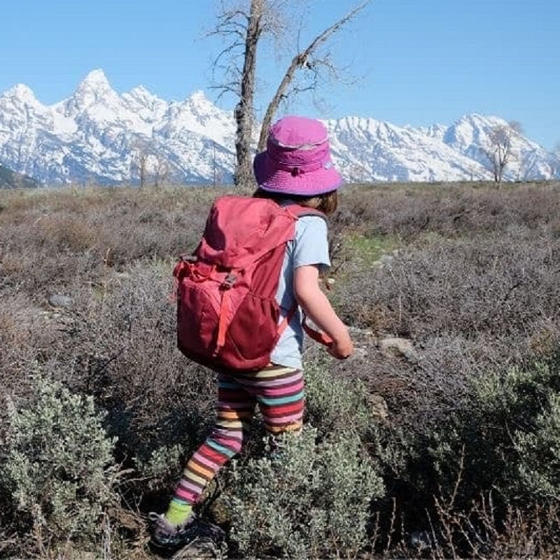 girl hiking with her red backpack